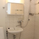 Vaalea kylpyhuone; osin laatta, harmaa muovimatto